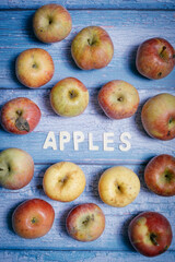 Yellow and red tasty apple fruit with apples word written won wooden letters on a blue wooden board