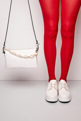 Woman's legs in red tights and white sneakers.