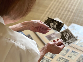 たくさんのアルバムを広げて写真を見る高齢女性の手元 - obrazy, fototapety, plakaty