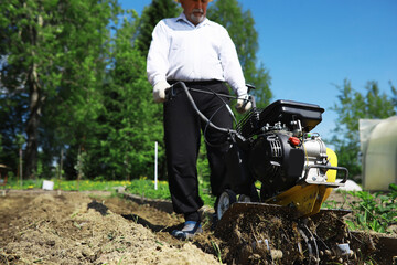 The farmer is digging a garden. A man with a harvester plows the garden. The gray-haired grandfather mows the garden.