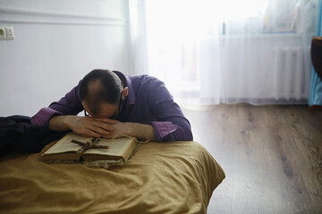 Man reading and pray from the holy bible near the bed in the evening. Christians and Bible study concept. Studying the Word Of God in church.