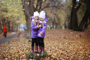 Fototapeta premium Young family on a walk in the autumn park on a sunny day. Happiness to be together.