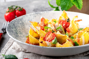 Pasta Conciglioni with bolognese sauce, tomatoes, parsley and parmesan. Original Italian pasta dish baked on a plate