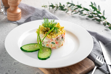Russian salad Olivier with mayonnaise, egg, potatoes and sausage, served in a culinary ring on a plate.