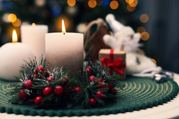 Beautiful burning candles and Christmas decor on white table against festive lights. Space for text