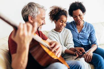 Man singing and playing guitar for his daughter and his wife.