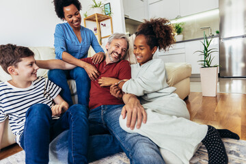 Young family watching TV together at home and having fun together.