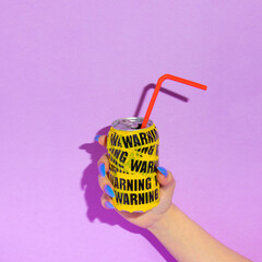 Summer creative layout with woman hand with long nails holding soda can wrapped in warning packing...