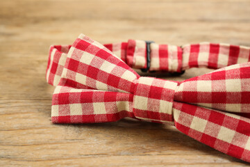 Stylish red and white gingham bow tie on wooden background, closeup