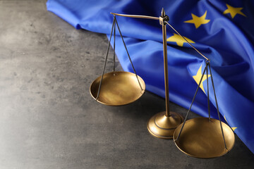 Scales of justice and European Union flag on grey table, above view. Space for text