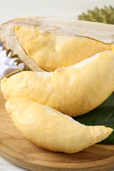 Pieces of fresh ripe durian on wooden plate, closeup