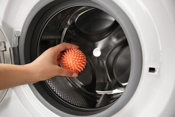 Woman putting dryer ball into washing machine, closeup