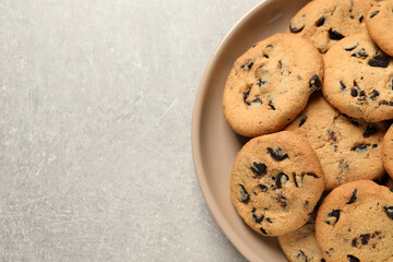 Plate with delicious chocolate chip cookies on grey table, top view. Space for text