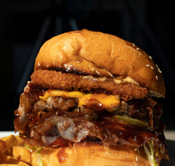 Tasty grilled burger with with beef, cheese, vegetables. Delicious grilled Cheeseburger on a dark background.