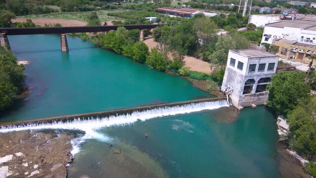 Drone footage over the Guadalupe River near the Faust Street bridge in New Braunfels, Texas with the River Mill and dam in the background.