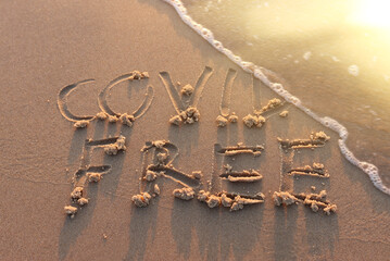 The words covid free written in sea sand. Concept of summer vacation and maintaining good health