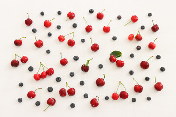 Top view image of colorful assorted mix of berries, blueberry and sweet cherry over wooden white background