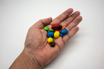 Rainbow Colored Candy Coated Chocolate Buttons in hand isolated on White