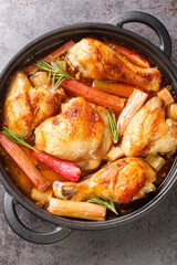 Baked chicken with rhubarb and white wine close-up in a frying pan on the table. Vertical top view from above