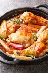 Baked chicken with rhubarb and white wine close-up in a frying pan on the table. vertical