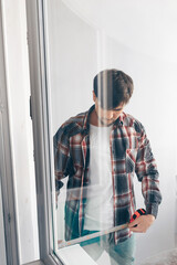 a builder worker measures a window in an apartment with a construction tape measure