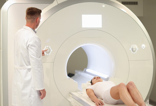 In medical laboratory male radiologist controls MRI or CT scan with female patient
