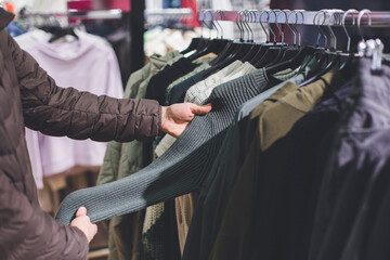 Many wooden plastic racks hangers with denim clothes male fashion dressing outfit in a shopping mall photo with selective focus. Making choice in a market.