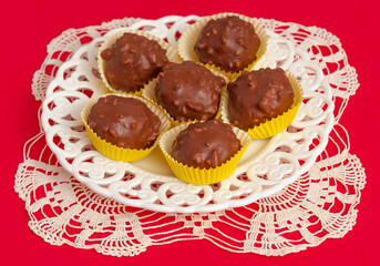 Tasty chocolate candy ball shapes with filling and nuts, on red background. Fill the entire frame.