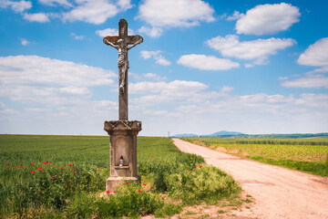 Fototapeta na wymiar A dirt road with a cross in the hungarian countryside in summer