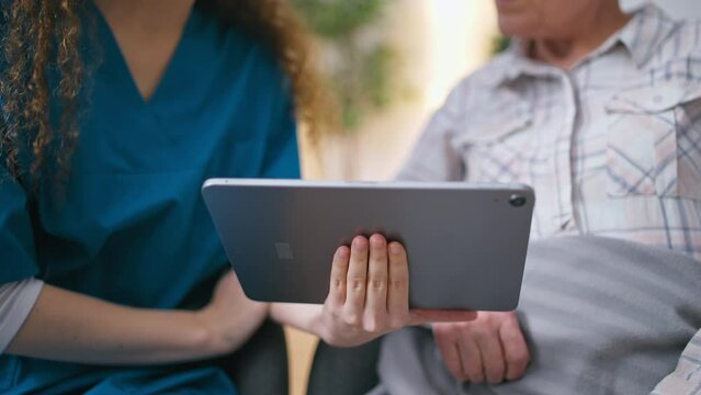 Female volunteer teaching mature woman how to use tablet, modern technology