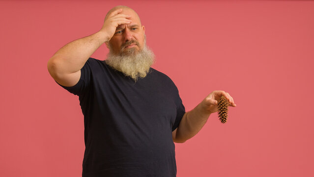 A man with a gray beard with a bump in his hand holds his head on a colored background. The concept of male potency.