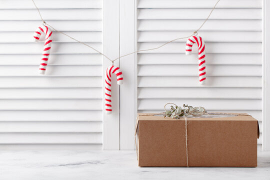Christmas gift, present box with candy cane decoration. White wooden blindes background. Copy space.