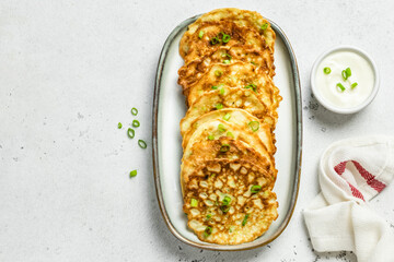 Healthy zucchini pancakes with sour cream. Top view, copy space, flat lay.