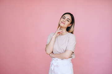 Girl in casual clothes playfully looking at the camera touching her face on an isolated background