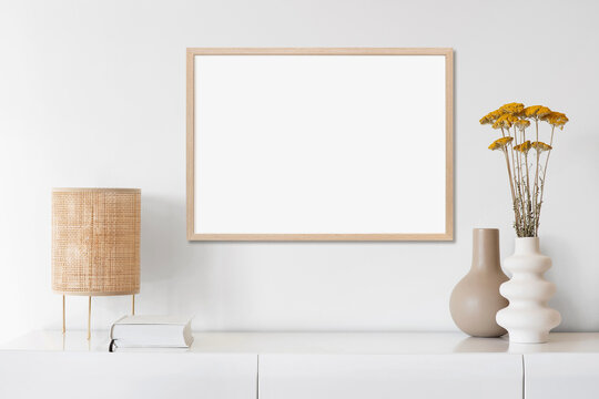 Blank picture frame mockup on white wall. Artwork in minimal interior design. View of modern boho style interior with canvas for painting or poster on wall. Minimalism concept