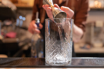 barman preparando coquetel em copo de vidro.