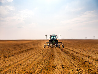 Tractor drilling seeding crops at farm field. Agricultural activity.