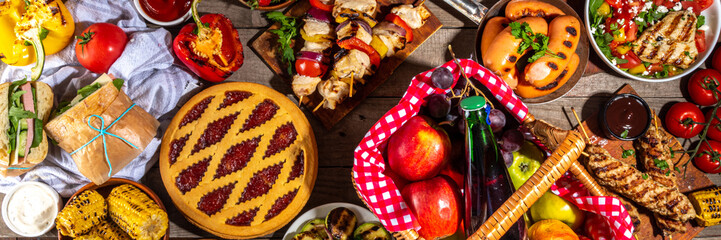 Various picnic barbeque food and drink flatlay. Summer bbq picnic food, assorted grilled meats, kebabs, vegetable, fruit salad, traditional picnic summer pie cake, sandwiches, top view copy space