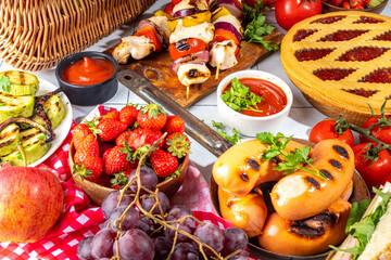 Various picnic barbeque food and drink flatlay. Summer bbq picnic food, assorted grilled meats, kebabs, vegetable, fruit salad, traditional picnic summer pie cake, sandwiches, top view copy space