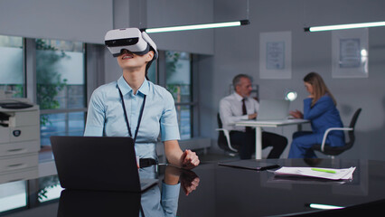 Asian female engineer in virtual reality goggles working in modern office