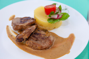 Beef cutlets meatballs with mashed potatoes on a white plate. Meat in sour cream sauce. Tomatoes and basil. Food in the restaurant. Lunch portion. Medallions.