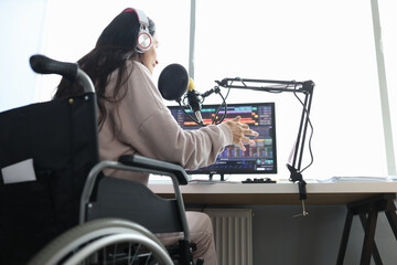 Woman in wheelchair speaks into microphone in front of computer