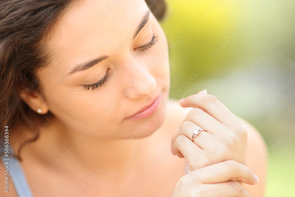 Wall mural serious woman looking at engagement ring in a park