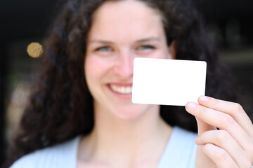 Happy woman showing blank credit card in the street
