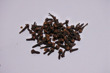Cloves or spices derived from dried flower buds of the Myrtaceae plant are native Indonesian spices, isolated and scattered in white