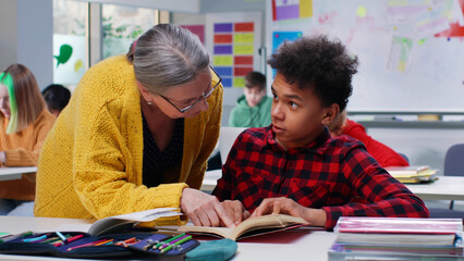Female teacher help African-American teen student in class