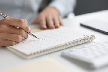 Closeup of person marking with pen and looking at date on calendar - Powered by Adobe