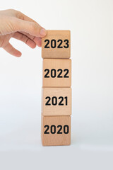 Hand dropping wooden cubes 2023 on top.
Beginning and beginning of new year 2023. Happy new year, goals, strategy concept.