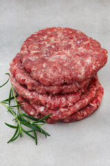 Raw free range 100% beef burger patties on mottled grey with copy space