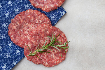 Raw free range 100% beef burger patties on mottled grey with copy space